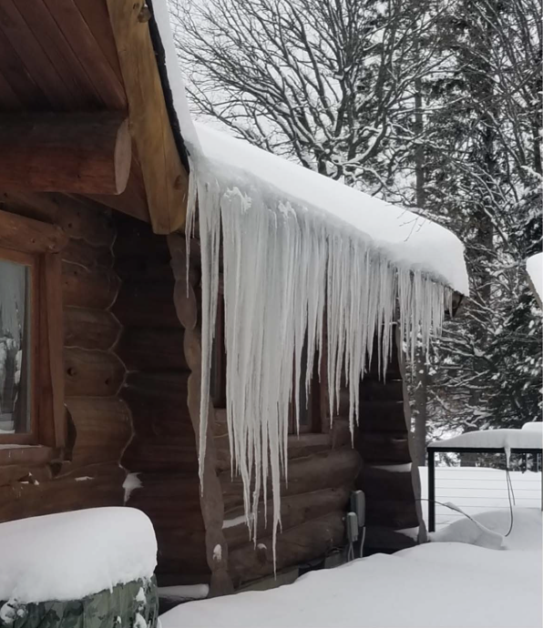 Long icicles hanging from a snowy roof edge